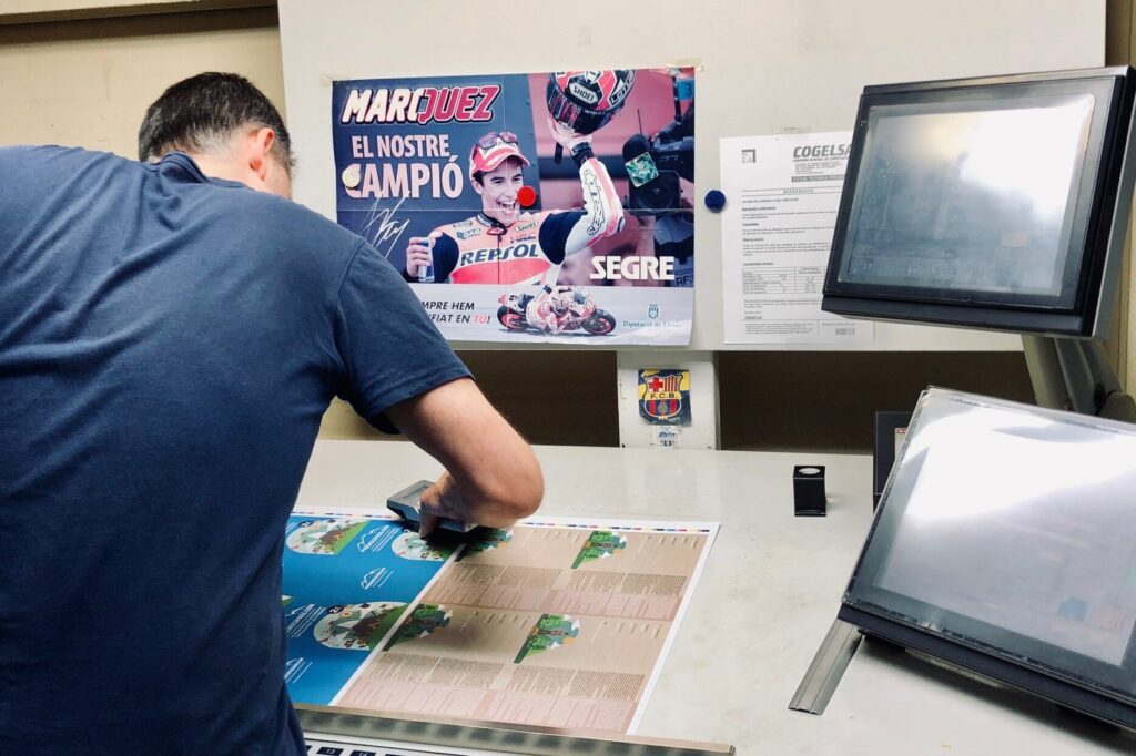 Operario realizando un control de color en el taller de la imprenta de Lleida con un espectrofotómetro